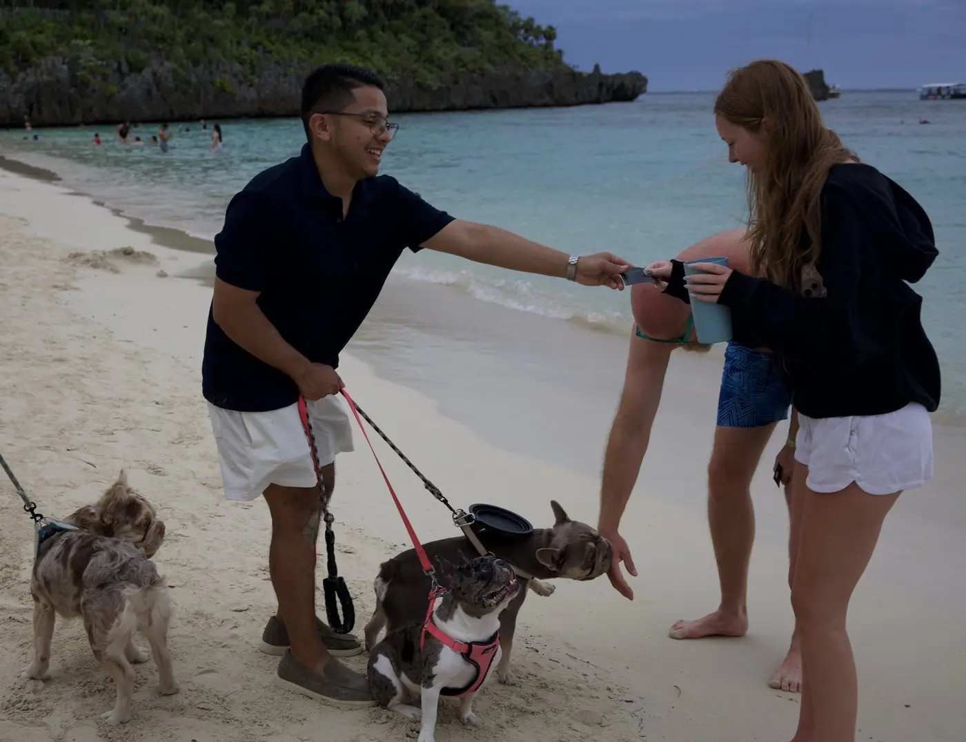 Jean intercambia una tarjeta con una visitante en la playa, junto a los Frenchies